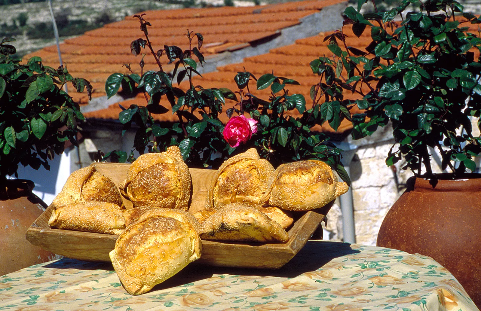 A wooden tray filled with traditional Cypriot flaounes outdoors